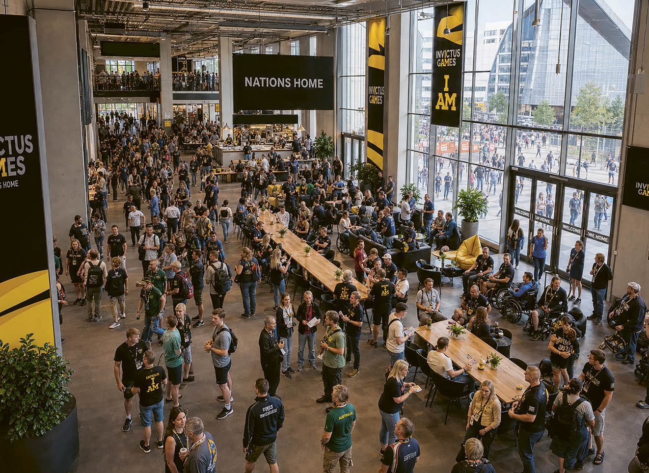 A large group of people are in a building, walking around and socializing. Description generated by AI