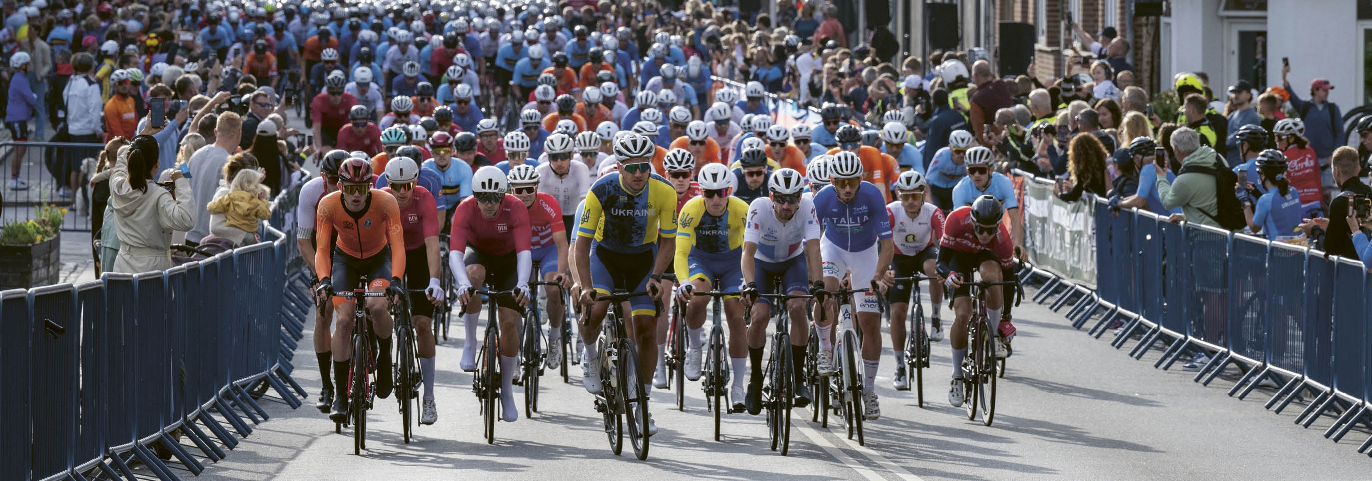 A group of bicyclists riding down a street. Description generated by AI