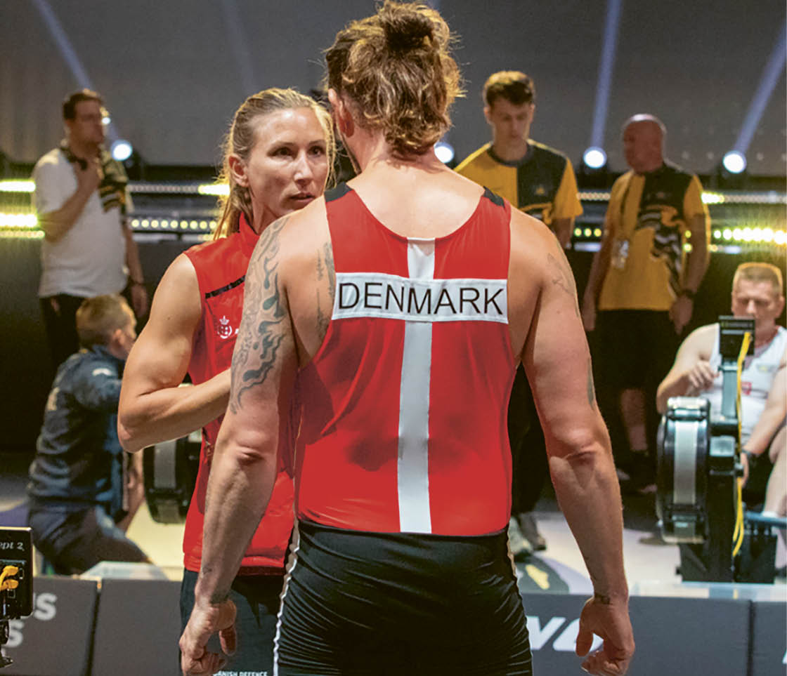 A man wearing a red and white shirt with the word Denmark on it. Description generated by AI