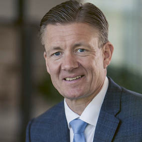 A man wearing a blue shirt and a blue tie. Description generated by AI