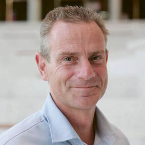 A man wearing a blue shirt and white collar. Description generated by AI