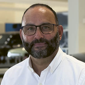 A man wearing glasses and a white shirt. Description generated by AI
