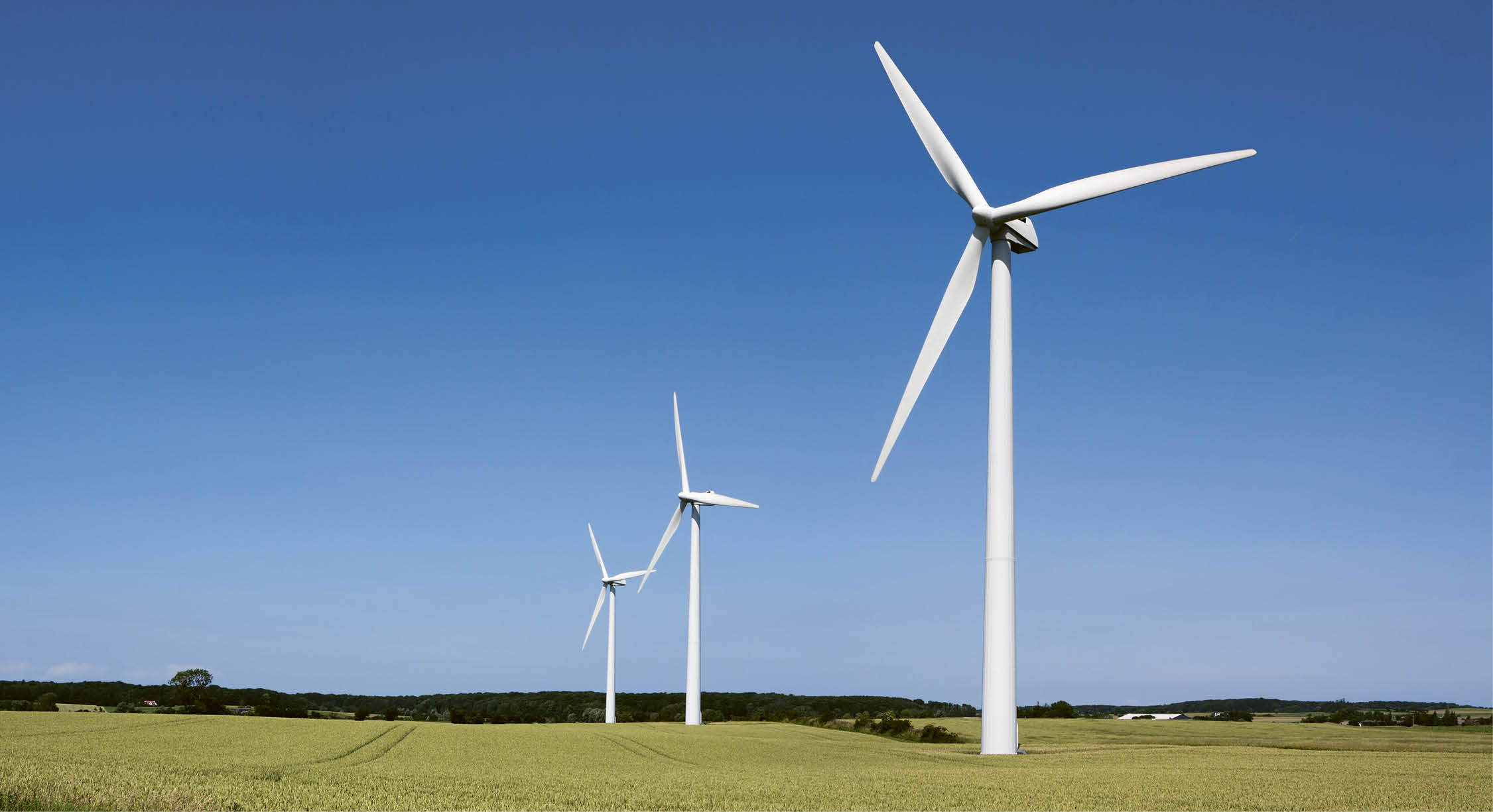 Three wind turbines in a field. Description generated by AI