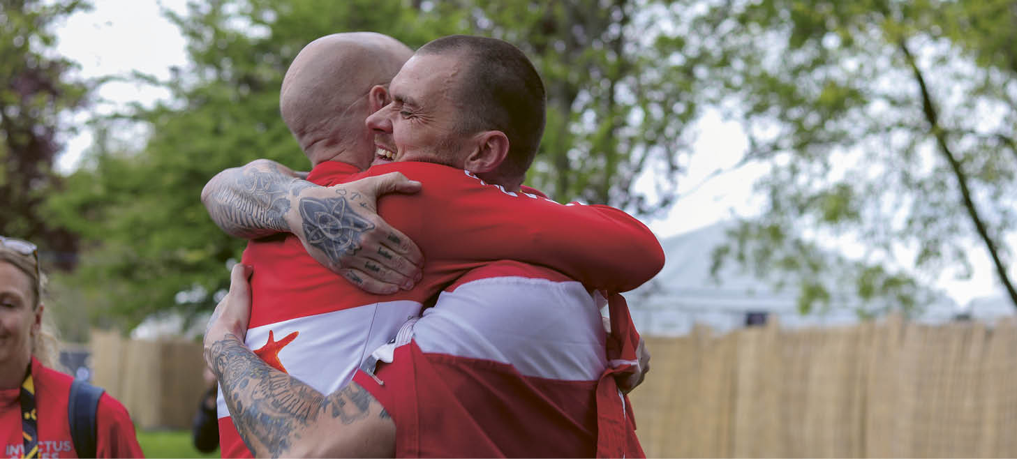 Two men wearing red shirts hugging each other. Description generated by AI