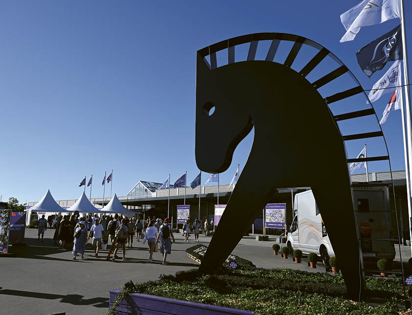 A black horse statue in front of a white building. Description generated by AI