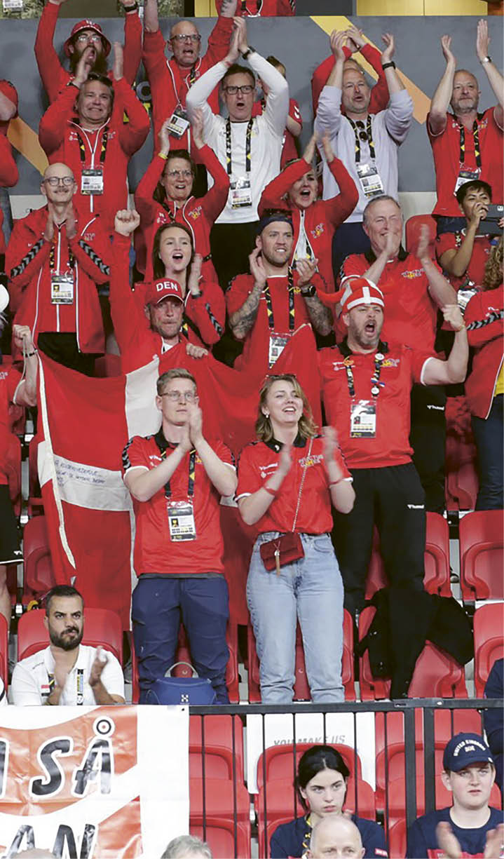 A group of people wearing red shirts and holding up their hands. Description generated by AI