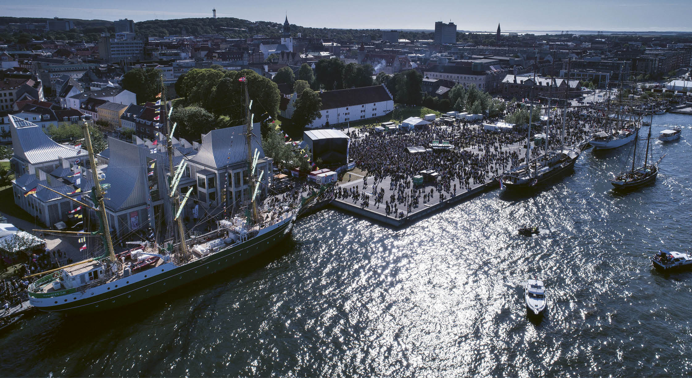 A large boat is docked in a harbor with a crowd of people around it. Description generated by AI